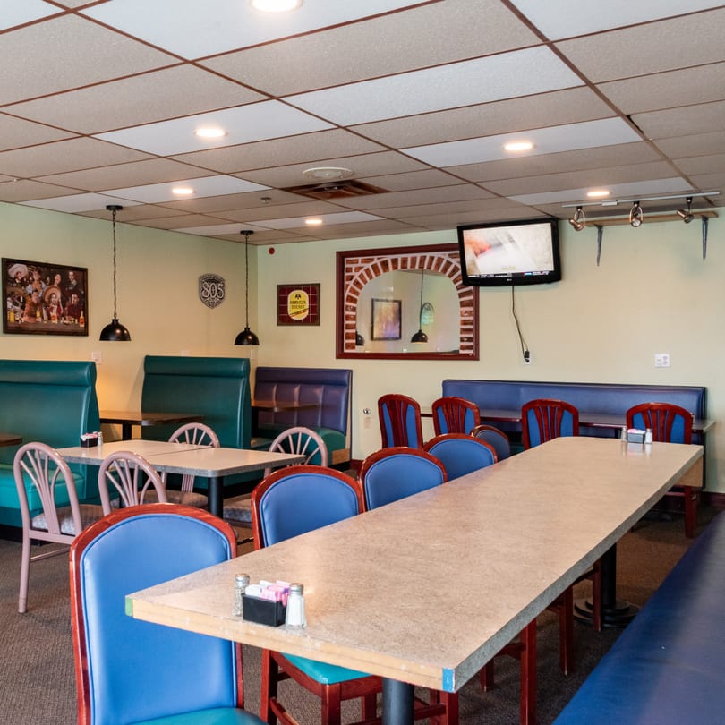 Interior of El Ranchero, a Mexican restaurant, with teal booths, blue chairs, and a long table.